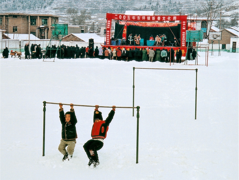 16、《鄉鎮文化周》2005年,淄博淄川東坪鄉,每逢春節假日,淄博市三個劇團都到鄉村進行演出活動,這是市五音劇團冒著大雪在東坪進行演出,孩子們看不懂古裝戲,就在單杠上玩耍。(劉統愛).jpg