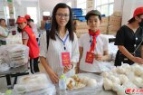 一人一份盒飯,兩葷兩素、雞腿米飯……24日中午,記者來到壽光洪水災(zāi)區(qū)營里鎮(zhèn)最大的一個(gè)安置點(diǎn)營里鎮(zhèn)第二初級中學(xué),恰逢安置點(diǎn)在分發(fā)午餐。圖為在營里鎮(zhèn)第二初中安置點(diǎn)服務(wù)的義工母子。（記者王磊 劉琛 沈廣安 馮煒程）