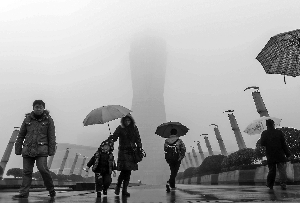 13日,行人冒雨走在霧霾籠罩下的杭州市區的一個廣場附近。新華社發